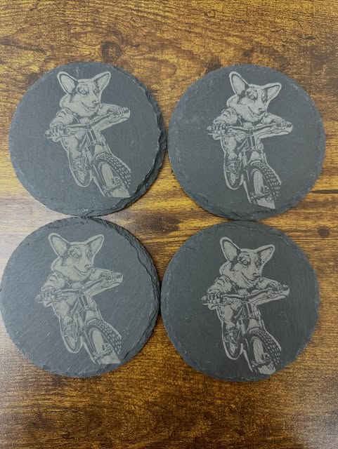 Set of four slate coasters engraved with a corgi riding a bike