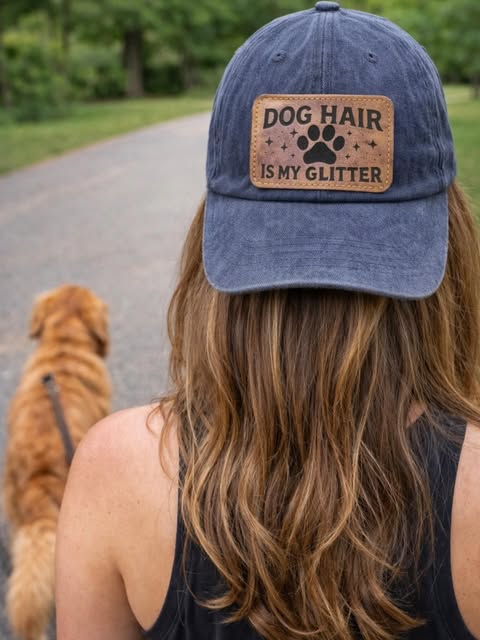 Woman wearing a backwards denim cap with a 'Dog hair is my glitter' leather patch
